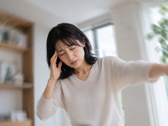 めまいやふらつきで頭に手を当てている女性